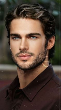 a man with long hair and blue eyes looks into the camera while wearing a brown shirt