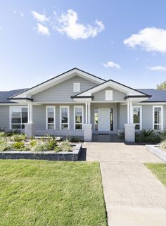 a gray house with white trim on the front door and windows, grass in front