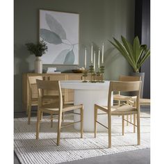 a dining room table and chairs with candles in the middle, on a rug next to it