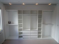 an empty room with white shelves and drawers