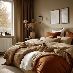 a large bed sitting next to a window covered in blankets and throw pillows on top of it