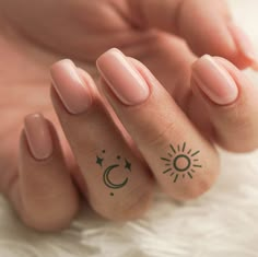 a woman's hand with two small tattoos on her fingers and one has a sun and moon