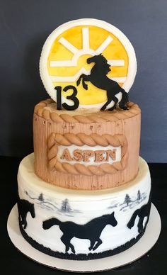 a three tiered cake decorated with horses and the number thirteen on it's side