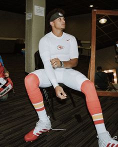 a man sitting on top of a chair wearing white and orange striped leggings