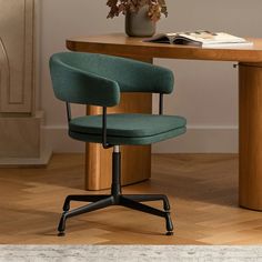 an office chair sitting in front of a desk with a book on it and a potted plant