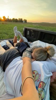 a woman laying on top of a bed next to a man in the back of a truck