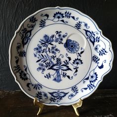 a blue and white plate sitting on top of a wooden table next to a black wall