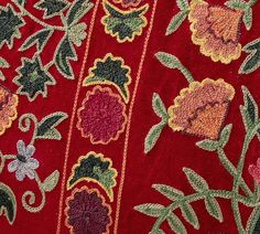 close up view of an embroidered fabric with flowers and leaves on red background, from the side