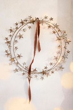 a metal wreath with stars hanging from it's side on a wall next to some lights