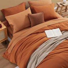 a bed with an orange comforter and two brown pillow cases on top of it