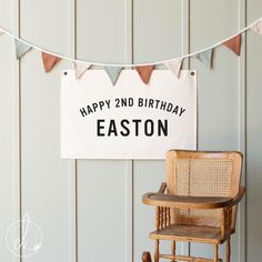 a happy 2nd birthday banner hanging on a wall next to a wooden chair and rocking chair