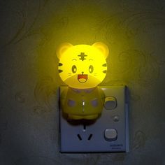 a yellow light that is on top of a white electrical outlet in the shape of a tiger