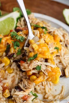 a white plate topped with rice covered in chicken and vegetables next to lime wedges