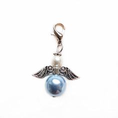 a blue pearl and silver charm with angel wings on the front, hanging from a metal hook