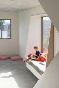 a young boy sitting on top of a bed in a bedroom next to a window