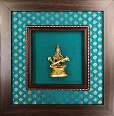 a gold statue in a wooden frame on a blue wall