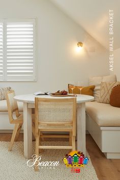 a table and chairs in a small room with white walls, wood flooring and wooden shutters