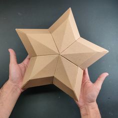 a hand is holding an origami star in front of a black table top