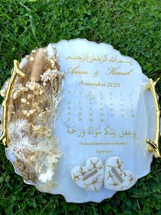 a white plate with some flowers on top of it in the grass next to a calendar