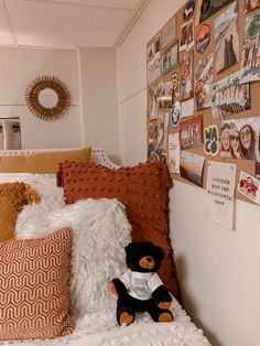 there is a teddy bear on the bed with many pictures on the wall behind it