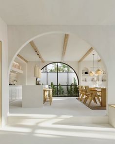 an arched doorway leads to the kitchen and dining area in this modern house with white walls