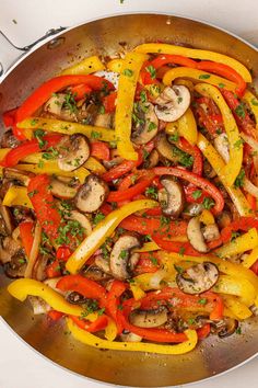 a pan filled with peppers and mushrooms on top of a stove