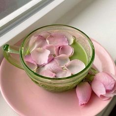 pink flowers are in a green cup on a pink plate