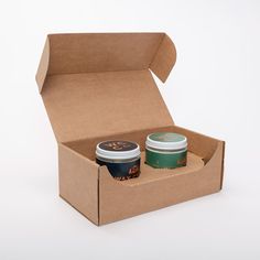 two cups of coffee in a cardboard box with the lid open on a white background