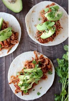 three tortillas with shredded meat, avocado and cilantro on top