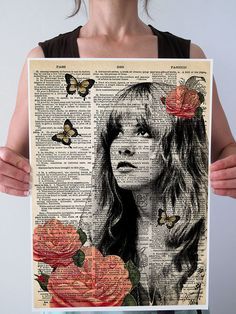 a woman holding up a piece of art with roses and butterflies on the pages in front of her face