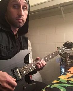 a man in a hoodie is playing an electric guitar