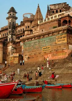 several boats are docked in front of an old building on the water's edge