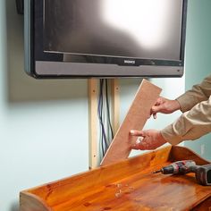 a man sanding wood in front of a flat screen tv