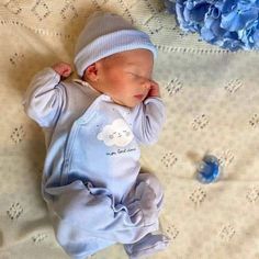 a baby laying on top of a bed next to blue flowers