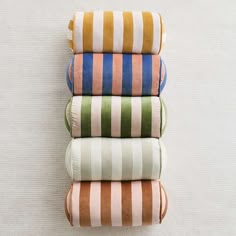 four folded towels stacked on top of each other in different colors and patterns, all laying side by side