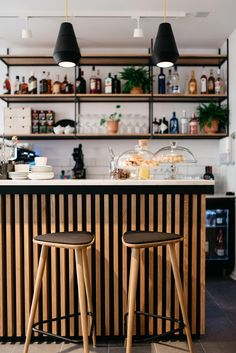 two wooden stools sitting in front of a bar