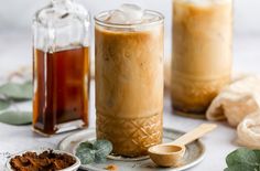 two jars filled with liquid sitting on top of a table next to spices and spoons