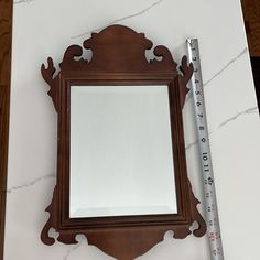 a mirror sitting on top of a white counter next to a ruler and a wooden frame