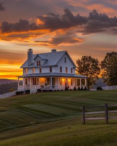 a large white house sitting on top of a lush green field under a cloudy sky