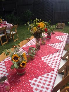 the table is set with sunflowers and other flowers in vases on it