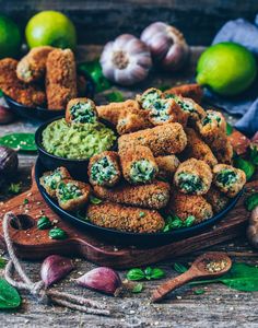 some food is in a bowl on a wooden table next to garlic and limes