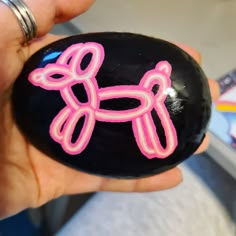 a person holding a black and pink rock with an image of a dog on it