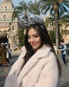 a woman wearing a tiara and posing for a photo in front of a castle