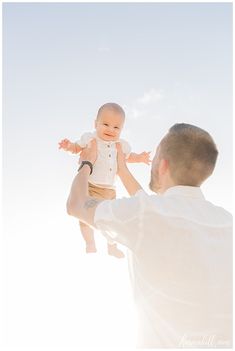 a man holding a baby up in the air