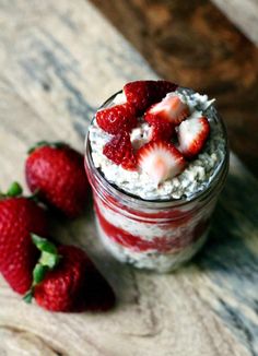 two strawberries sit on the table next to a jar of oatmeal