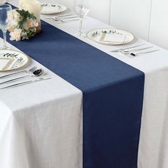 the table is set with white and blue plates, silverware, and napkins