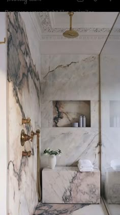 a bathroom with marble walls and flooring is shown in this image, there are two shelves on the wall