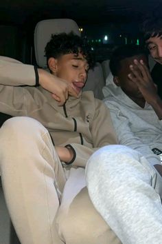 two young men sitting in the back of a car