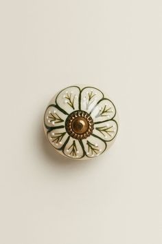 a white and green flower shaped cabinet knob on a white surface with a brown center