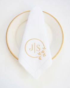 a white napkin with the initials j s on it sitting on top of a gold rimmed plate